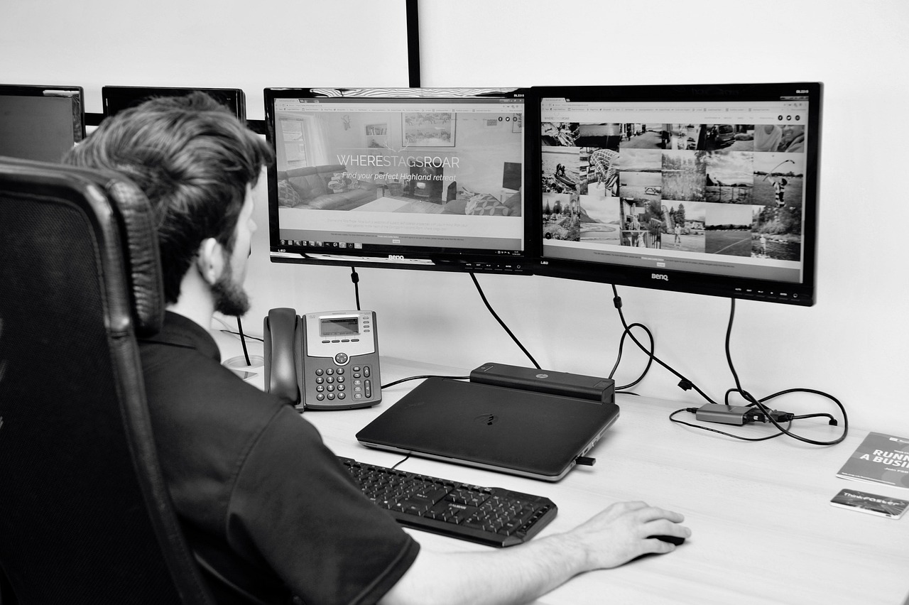Web designer working on dual monitors – illustrating standard templates vs full custom website builds.
